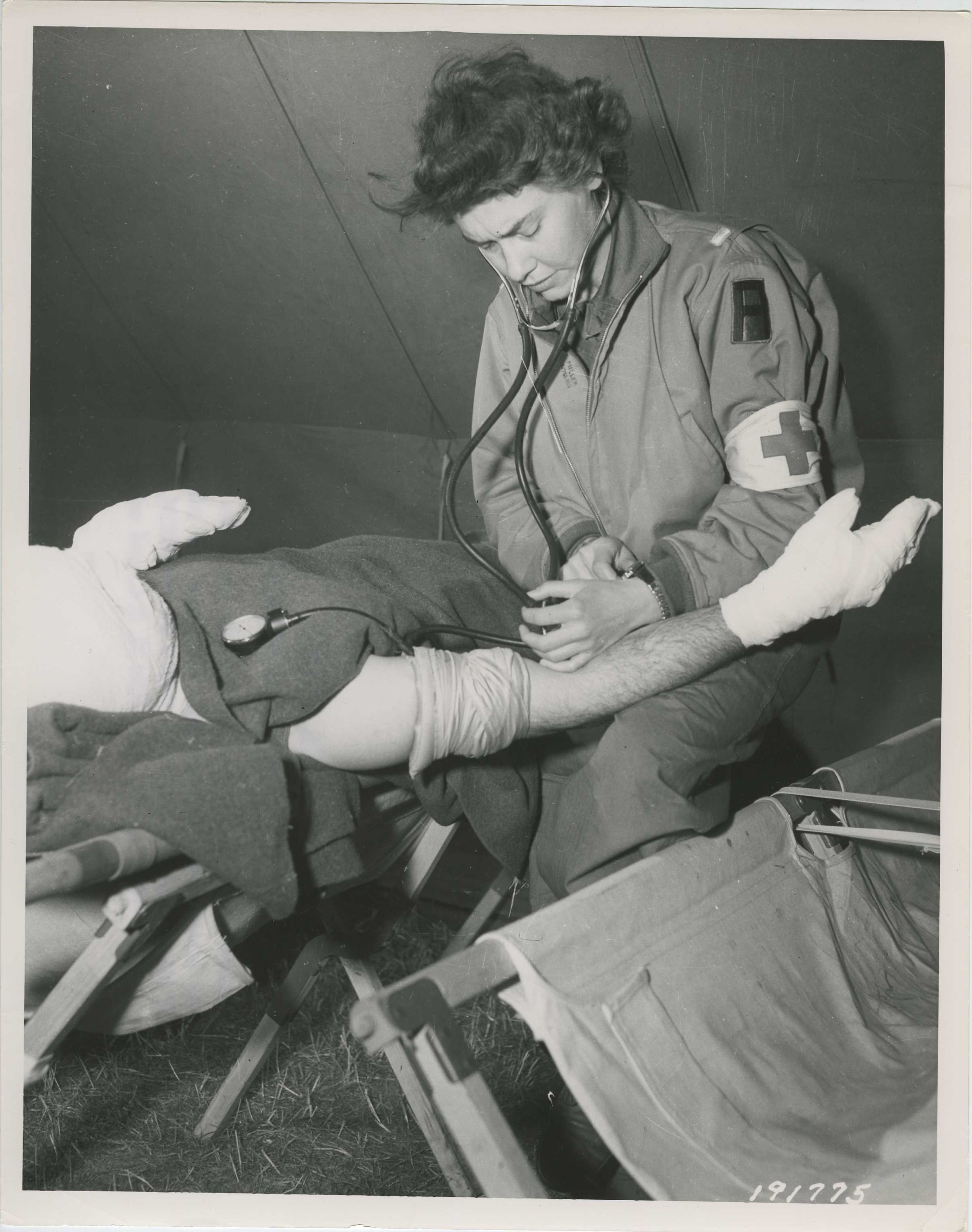A medical assistant in scrubs taking a seated patient's blood pressure in a bright outpatient clinic
